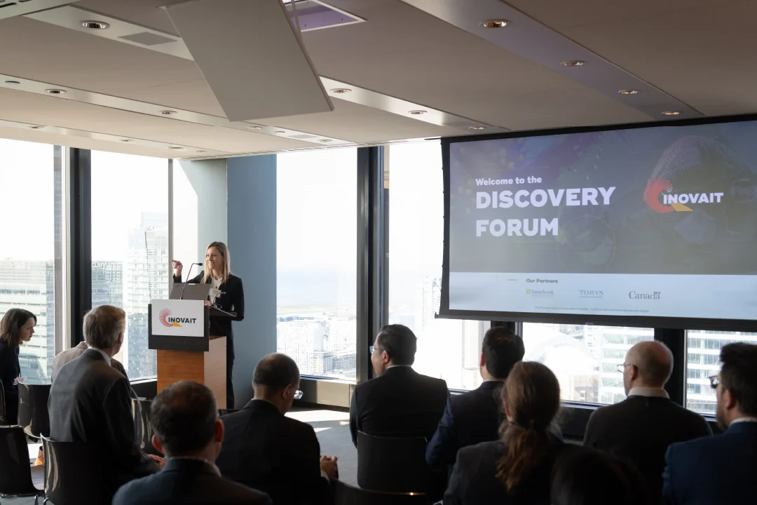 At the INOVAIT Discovery Forum, Yolande Dufresne delivers the welcoming remarks from a podium.